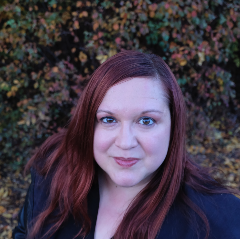 Das Porträt einer Frau (Margareta Ferec-Petric). Sie schaut von hinten geradeaus und trägt ein dunkelblaues Oberteil. Im Hintergrund sind grüne Pflanzen zu sehen.