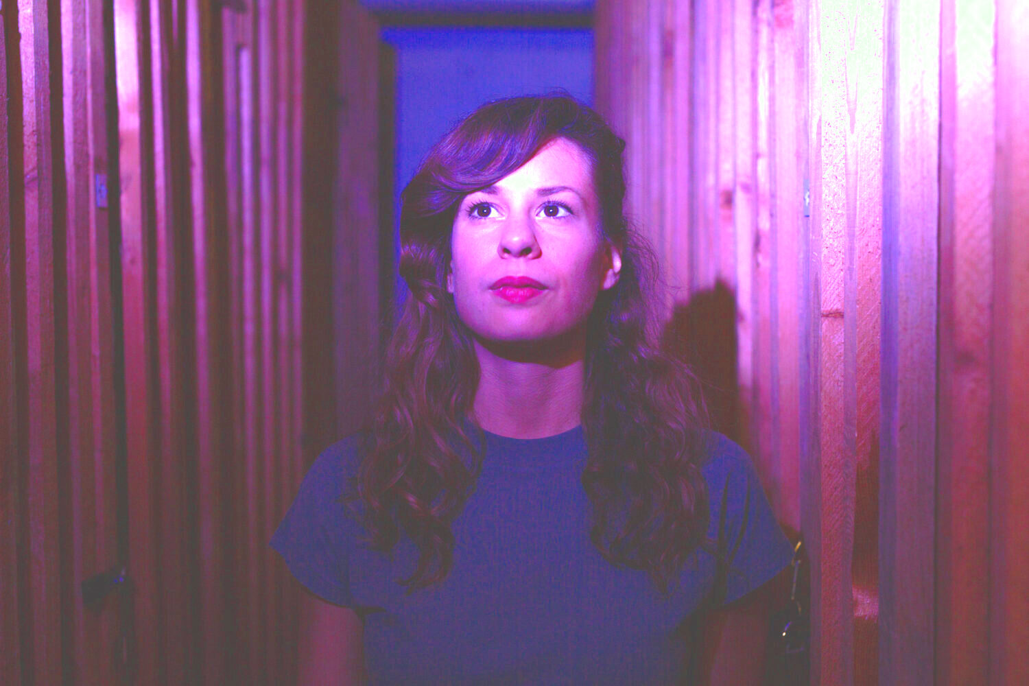 Zu sehen ist ein Portrait der Komponistin Georgia Koumará, sie ist eingetaucht in violettfarbenes Licht.